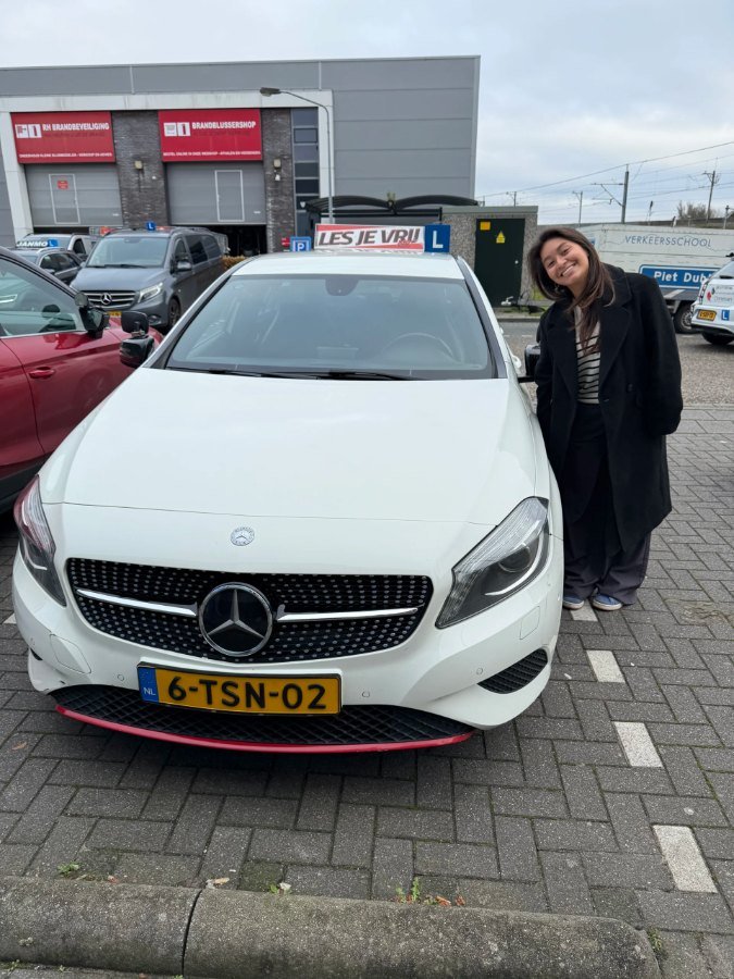 Geslaagde leerling naast de lesauto in het Westland
