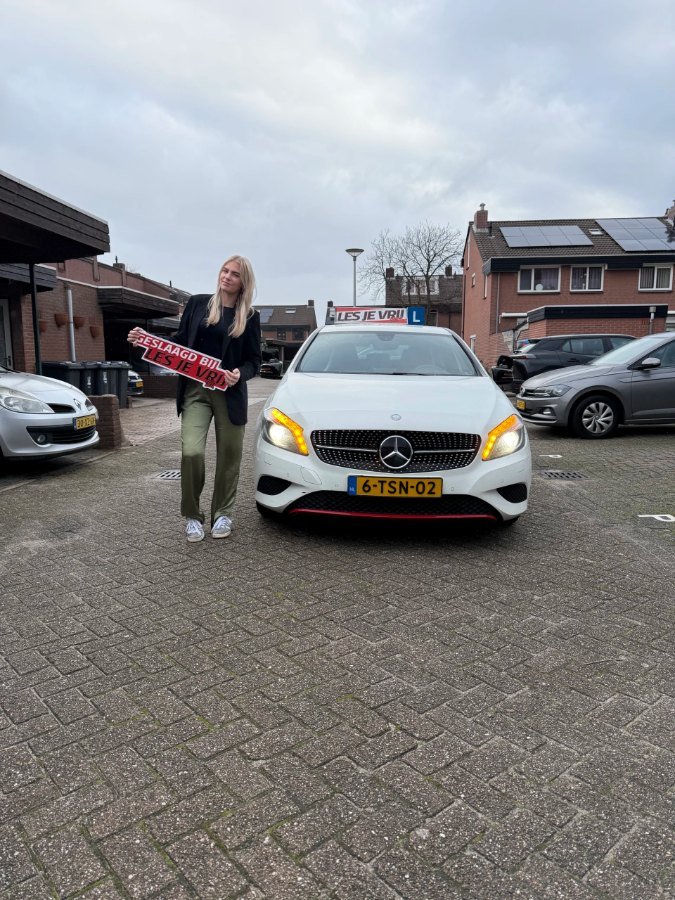 Geslaagde leerling van Rijschool Les je Vrij met het lesbord