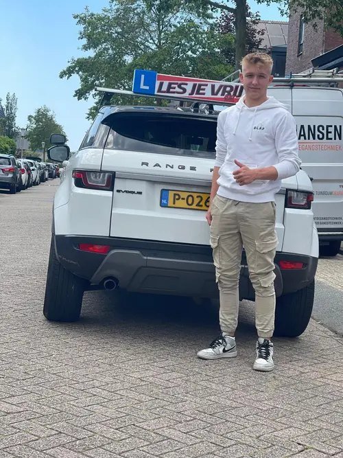 Geslaagde leerling naast de lesauto in het Westland