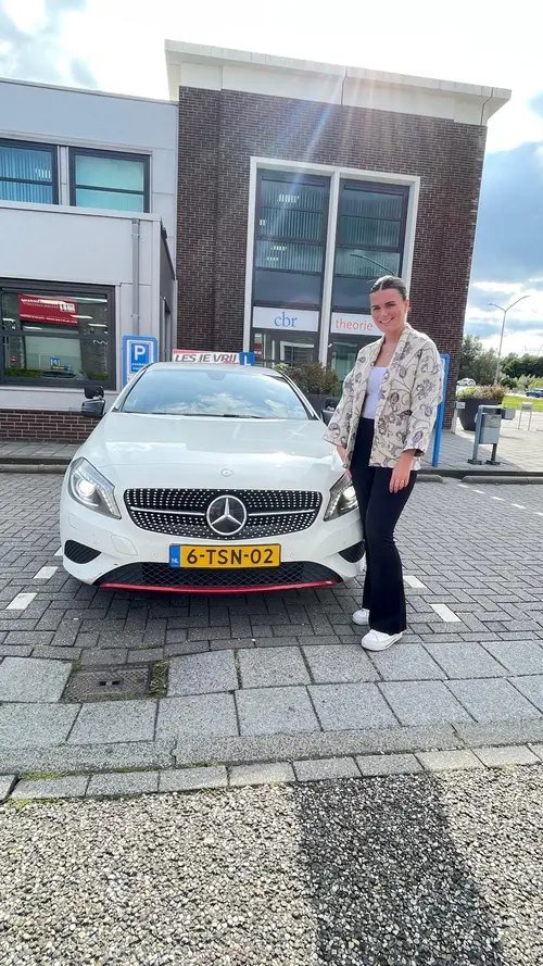 Geslaagde leerling van Rijschool Les je Vrij met het lesbord