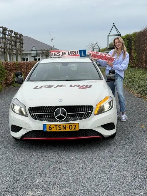 Geslaagde leerling naast de lesauto in het Westland