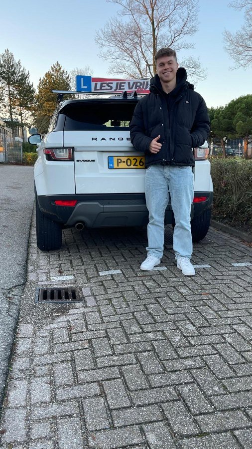 Geslaagde leerling naast de lesauto in het Westland