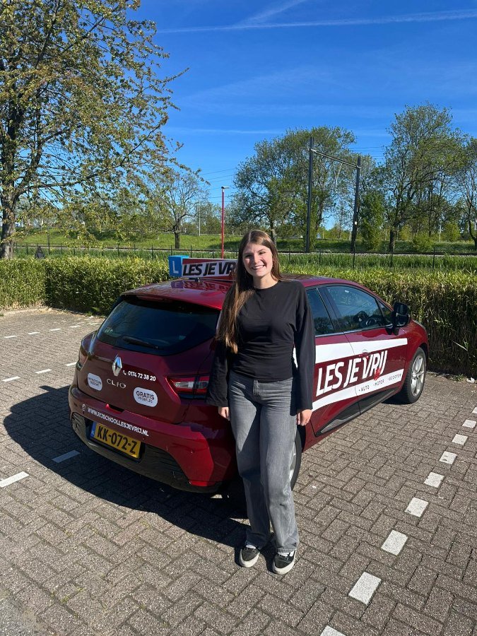 Geslaagde leerling van Rijschool Les je Vrij met het lesbord
