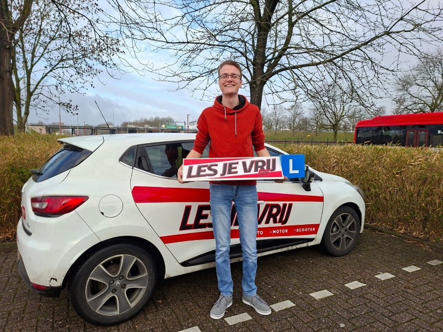 Geslaagde leerling naast de lesauto in het Westland